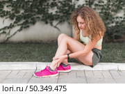 woman sitting park looking injured ankle. Стоковое фото, агентство Ingram Publishing / Фотобанк Лори