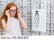 attractive young woman wearing eyeglasses standing neat snellen chart optica. Стоковое фото, агентство Ingram Publishing / Фотобанк Лори
