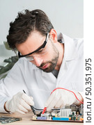 technician examining computer motherboard with digital multimeter. Стоковое фото, агентство Ingram Publishing / Фотобанк Лори