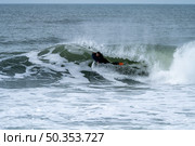 Bodyboarder performing a tube trick surfing ocean wavesurfing ocean wave on a cloudy winter day. Стоковое фото, агентство Ingram Publishing / Фотобанк Лори