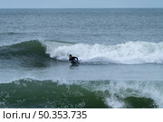 Bodyboarder performing a 360 trick surfing ocean wave on a cloudy winter day. Стоковое фото, агентство Ingram Publishing / Фотобанк Лори