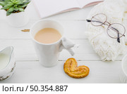 palmiers elephant ear puff pastry cookie with porcelain white tea cup wooden desk. Стоковое фото, агентство Ingram Publishing / Фотобанк Лори