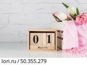 wooden calendar with 1st march near wooden crate with tulips scarf white desk. Стоковое фото, агентство Ingram Publishing / Фотобанк Лори