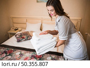 close up maid putting stack fresh white bath towels bed sheet. Стоковое фото, агентство Ingram Publishing / Фотобанк Лори