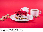 delicious strawberry jelly cheese cake white plate with brown sugar cubes against red backdrop. Стоковое фото, агентство Ingram Publishing / Фотобанк Лори