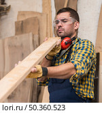 male carpenter seriously looking wooden plank. Стоковое фото, агентство Ingram Publishing / Фотобанк Лори