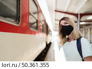 woman wearing fabric mask standing train. Стоковое фото, агентство Ingram Publishing / Фотобанк Лори