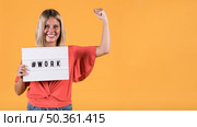 young deaf woman holding light box with hash tag work text flexing muscle yellow backdrop. Стоковое фото, агентство Ingram Publishing / Фотобанк Лори