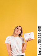 woman looking up holding menstruation calendar. Стоковое фото, агентство Ingram Publishing / Фотобанк Лори