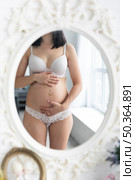 pregnant woman checking herself mirror. Стоковое фото, агентство Ingram Publishing / Фотобанк Лори