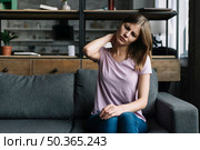 woman sitting sofa suffering from neck pain. Стоковое фото, агентство Ingram Publishing / Фотобанк Лори
