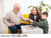 happy multi generational family assembling jigsaw puzzle together. Стоковое фото, агентство Ingram Publishing / Фотобанк Лори