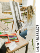 creative artist sitting stool sketching easel with black crayon. Стоковое фото, агентство Ingram Publishing / Фотобанк Лори