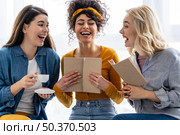 three women laughing together with book. Стоковое фото, агентство Ingram Publishing / Фотобанк Лори