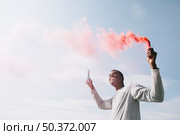 black man holding colored smoke bombs. Стоковое фото, агентство Ingram Publishing / Фотобанк Лори