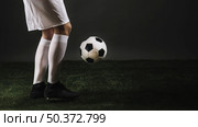 crop soccer player juggling ball dark studio. Стоковое фото, агентство Ingram Publishing / Фотобанк Лори