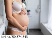 side view pregnant woman touching her belly. Стоковое фото, агентство Ingram Publishing / Фотобанк Лори
