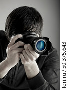Young man holding a professional DSLR camera and taking pictures. Стоковое фото, агентство Ingram Publishing / Фотобанк Лори