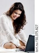 Beautiful young woman on bed working with a laptop. Стоковое фото, агентство Ingram Publishing / Фотобанк Лори