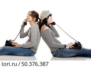 Two young women talking with old telephones - Isolated on white. Стоковое фото, агентство Ingram Publishing / Фотобанк Лори