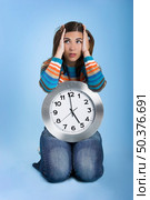 Beautiful women over knees holding a big clock in a blue background. Стоковое фото, агентство Ingram Publishing / Фотобанк Лори