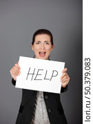 Stressed business woman imploring for help, holding a cardboard with the message "Help". Focus is on the cardboard. Стоковое фото, агентство Ingram Publishing / Фотобанк Лори