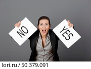 Business young woman trying to make a decision between Yes or No choice, over a gray background. Стоковое фото, агентство Ingram Publishing / Фотобанк Лори