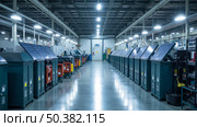 Modern indoor facility with rows of innovative solar power units, sleek dark green casings, bright overhead lights, advanced renewable energy technology, futuristic clean factory. Стоковое AI-изображение, AI-художник Павел Муравьев / Фотобанк Лори