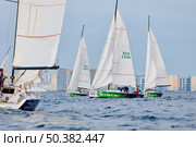 Russia, St.Petersburg, 13 June 2025: Sailing regatta in the Gulf of Finland at sunset, hot race of several yachts, teamwork, yachtsmen sitting on board the boat. Редакционное фото, фотограф Vladimir Drozdin / Фотобанк Лори
