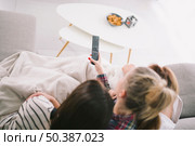 girlfriends watching tv cuddling sofa. Стоковое фото, агентство Ingram Publishing / Фотобанк Лори