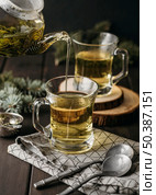 high angle hand pouring tea glass with teapot. Стоковое фото, агентство Ingram Publishing / Фотобанк Лори