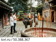 side view man woman praying temple with burning incense. Стоковое фото, агентство Ingram Publishing / Фотобанк Лори