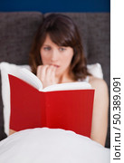Young woman reading a terror storie with a terrified expression. Стоковое фото, агентство Ingram Publishing / Фотобанк Лори