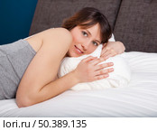 Beautiful young woman lying on the bed. Стоковое фото, агентство Ingram Publishing / Фотобанк Лори