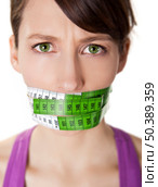 Portrait of a young  woman with a green measuring tape covering the mouth. Стоковое фото, агентство Ingram Publishing / Фотобанк Лори