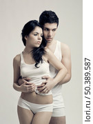 Beautiful and attractive young couple in underwear standing over a white background. Стоковое фото, агентство Ingram Publishing / Фотобанк Лори