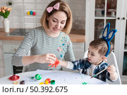 mother teaching little boy how paint eggs easter. Стоковое фото, агентство Ingram Publishing / Фотобанк Лори