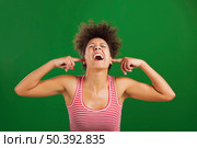 African woman covering ears with her hands, over a green background. Стоковое фото, агентство Ingram Publishing / Фотобанк Лори