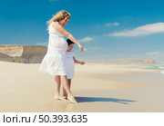 Beautiful pregnant woman and her little daughter on the beach pointing to the sand. Стоковое фото, агентство Ingram Publishing / Фотобанк Лори
