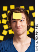 Happy student with a reminder on the head, and with more yellow paper notes in the background. Стоковое фото, агентство Ingram Publishing / Фотобанк Лори