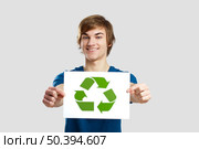 Casual young man holding a recycling sign to promote a green and better world, over a gray background. Стоковое фото, агентство Ingram Publishing / Фотобанк Лори