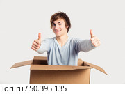 Portrait of a handsome young man a cardbox with thumbs up. Стоковое фото, агентство Ingram Publishing / Фотобанк Лори