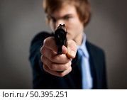 Stressed businessman holding and pointing a gun to the camera. Стоковое фото, агентство Ingram Publishing / Фотобанк Лори