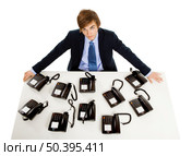 Young man in the office with a bunch telephones on his front. Стоковое фото, агентство Ingram Publishing / Фотобанк Лори