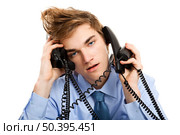 Young man sitting in the office and answering several phones at the same time. Стоковое фото, агентство Ingram Publishing / Фотобанк Лори