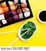 OLYMPUS DIGITAL CAMERA. sushi box plate with seaweed salad soy sauce yellow background. Стоковое фото, агентство Ingram Publishing / Фотобанк Лори