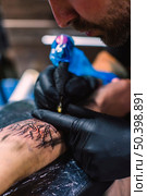 master doing tattoo arm with needle. Стоковое фото, агентство Ingram Publishing / Фотобанк Лори