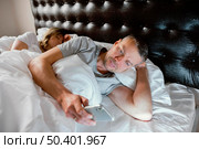 husband using mobile while wife is asleep. Стоковое фото, агентство Ingram Publishing / Фотобанк Лори