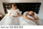wife using mobile while husband is asleep. Стоковое фото, агентство Ingram Publishing / Фотобанк Лори
