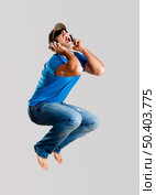 Young man jumping and listening music isolated over a gray background. Стоковое фото, агентство Ingram Publishing / Фотобанк Лори
